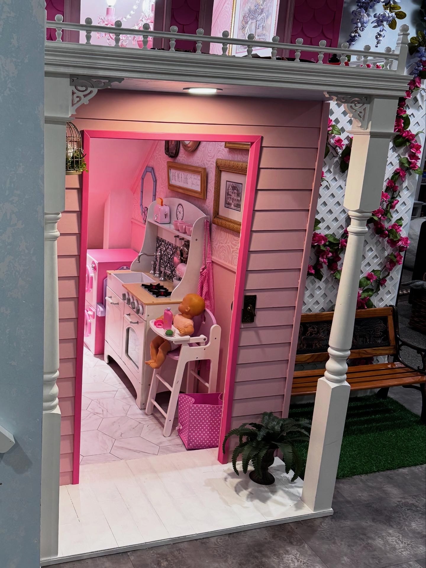 Pink bakery playhouse with lattice roses, turned columns, hex tile floor, and play kitchen interior