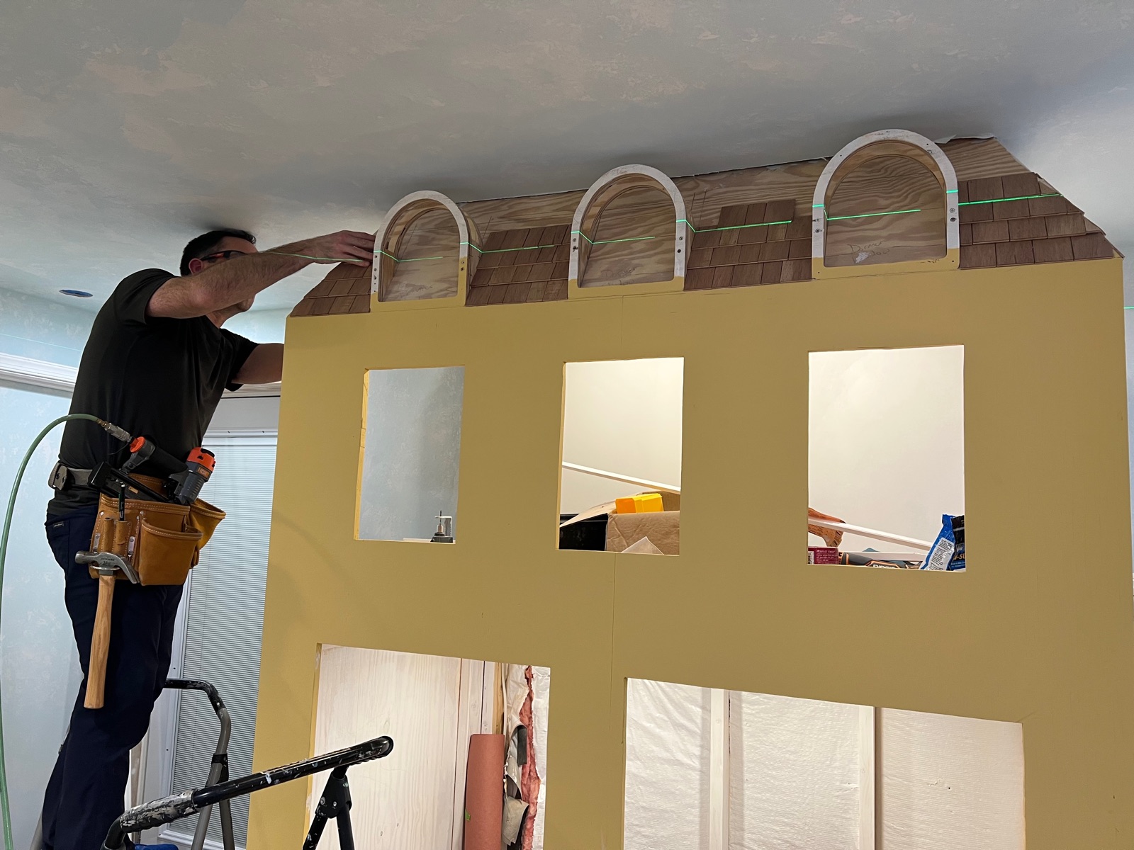 David Peterson on a ladder fitting dormer windows and birch shingles on a playhouse roof