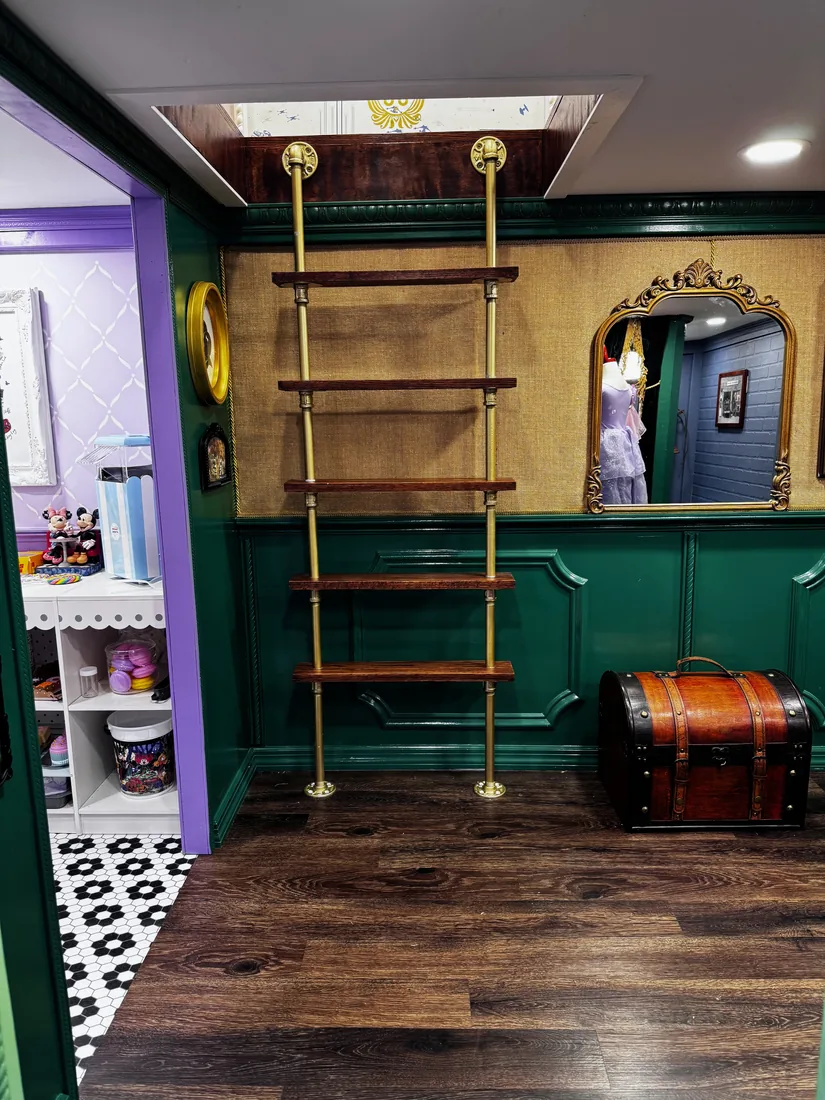A pipe ladder and open pipe shelving inside the Clothier's, beside a gilt mirror and a steamer trunk