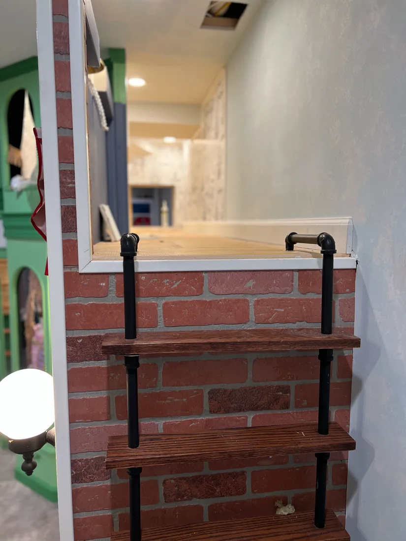 A custom pipe-and-wood ladder mounted on the Fire Station's red-brick wall, climbing to the loft