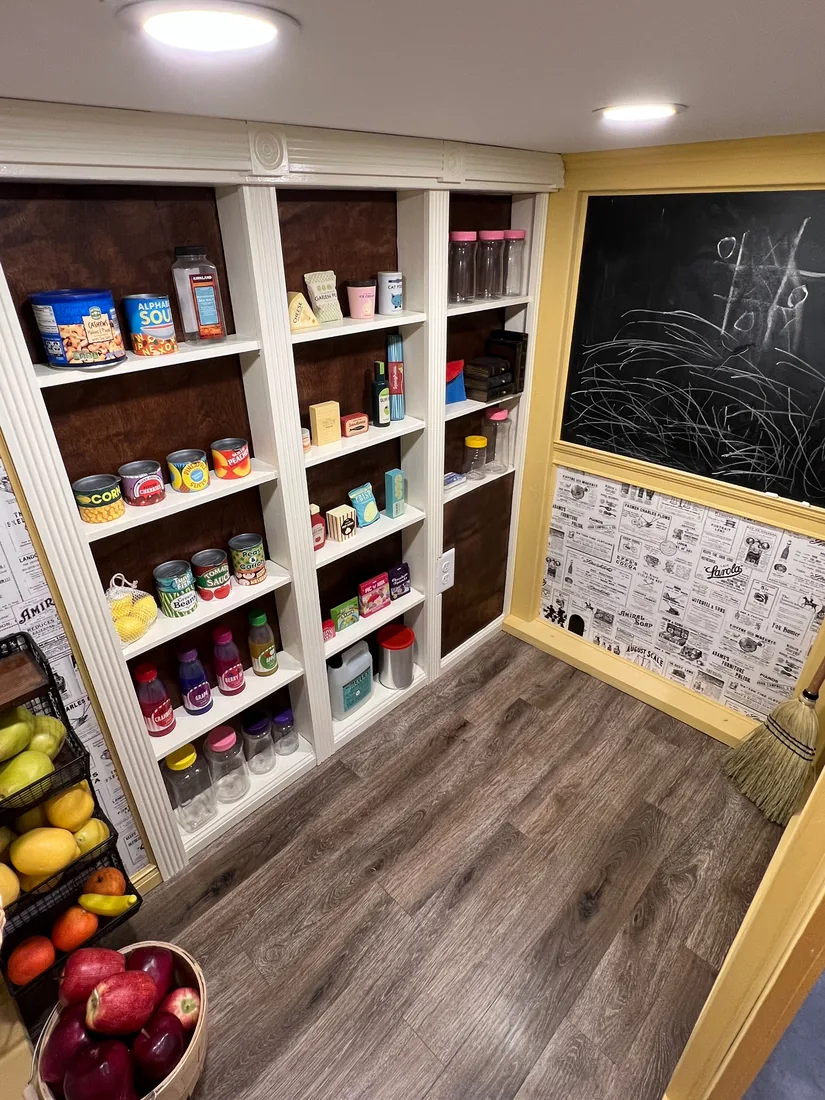 The Grocer's interior — floor-to-ceiling built-in shelving, a chalkboard, and a basket of apples