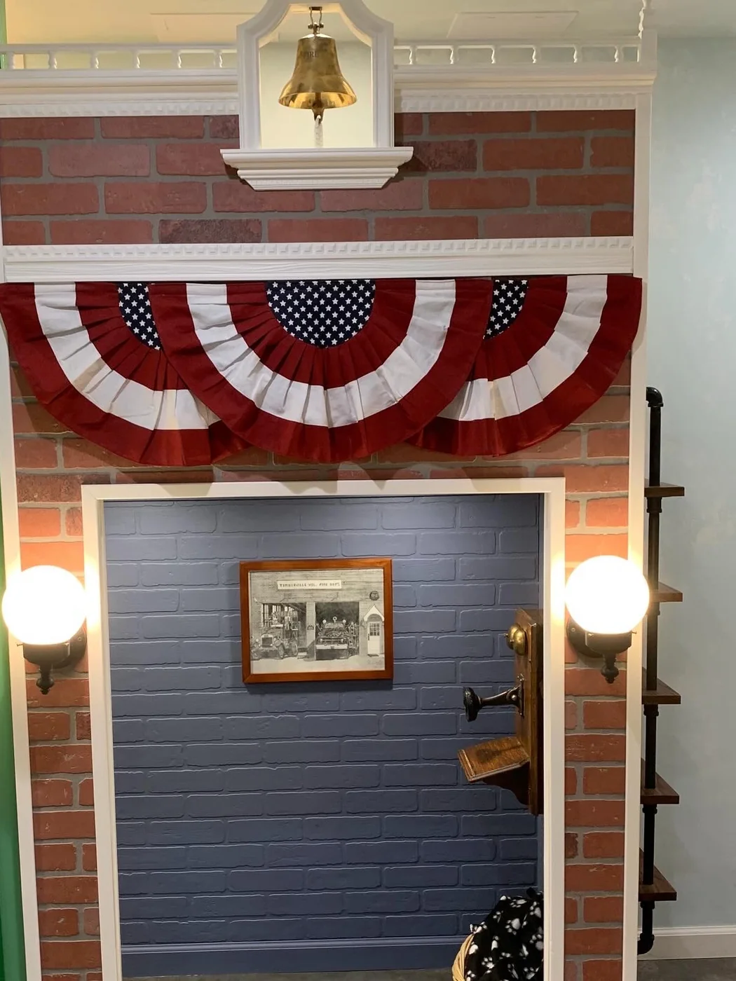 Jay Street Fire Station playhouse — a red-brick facade with a brass bell, bunting, and globe sconces