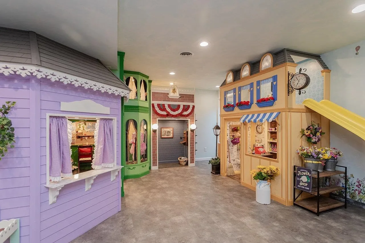The Main Street playhouse village — the Sweet Shoppe, the Clothier's, the Fire Station, and the Peterson Grocer with its slide