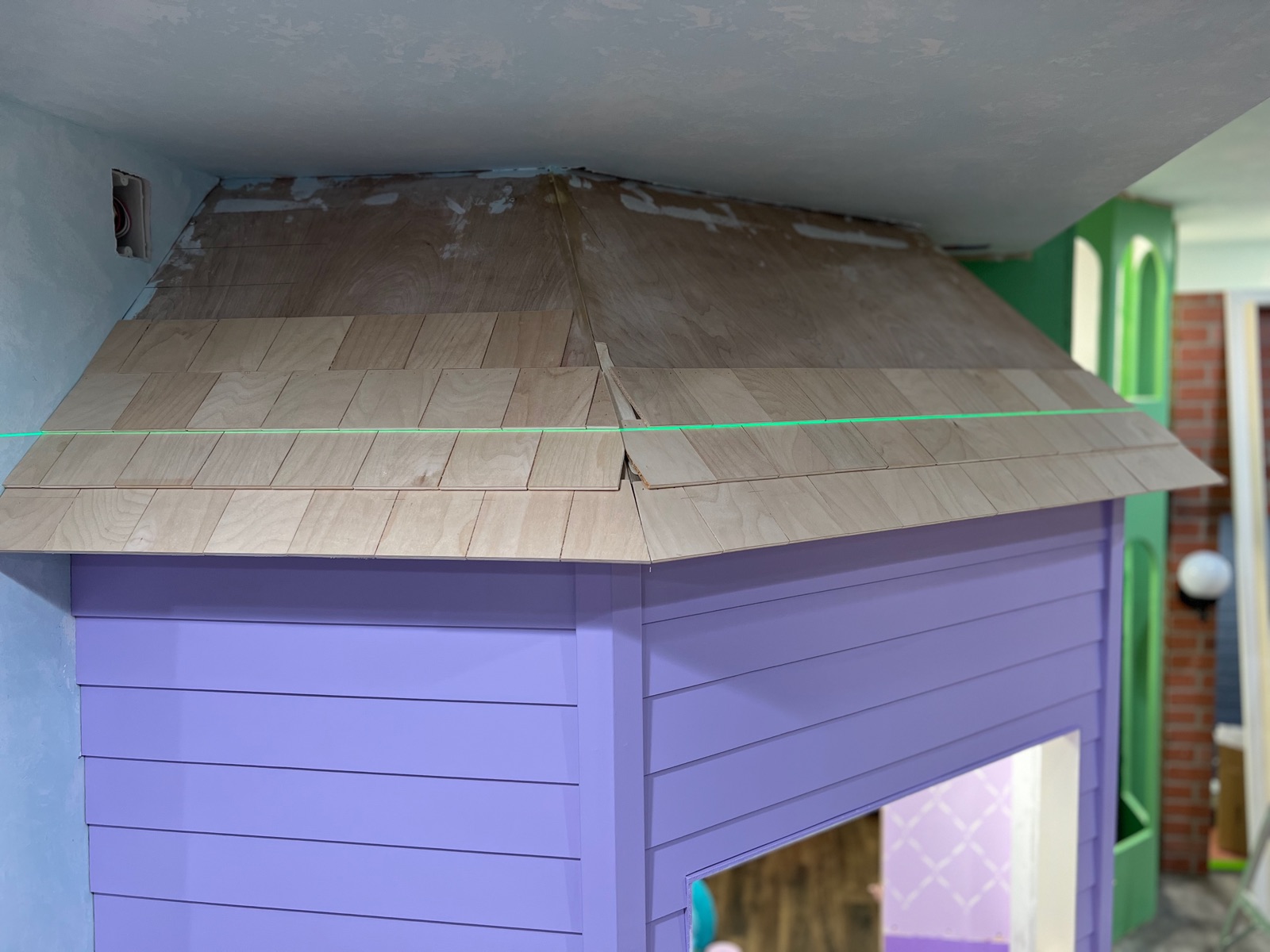 Sweet Shoppe roof shingling in progress with laser level and individual birch shingles